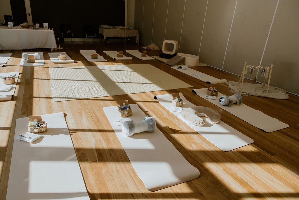 Rows of cream play mats set and waiting, with warm afternoon light streaming across the timber floor